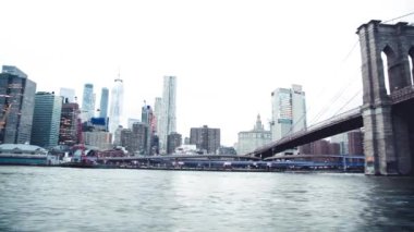 NEW YORK CITY - ARALIK 2018: Brooklyn Köprüsü 'nün altındaki hareketli bir tekneden Manhattan' ın modern silueti.