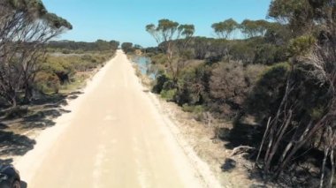 Kangaroo Island unpaved road along lake and trees, aerial view from drone - Australia.