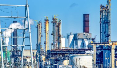Oil refinery industry view details of pipes with valves in a large refinery isolated on blue sky.