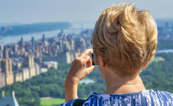 A happy elderly woman looking at New York panorama.