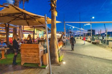 Malaga, İspanya - 14 Nisan 2023: Turistler gece liman boyunca yürüyorlar.