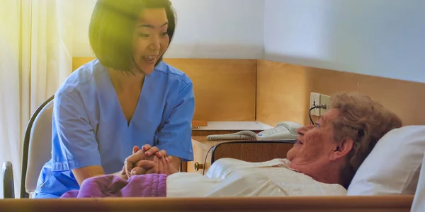 Young asian female doctor reassuring elderly retired woman in the hospital bed.