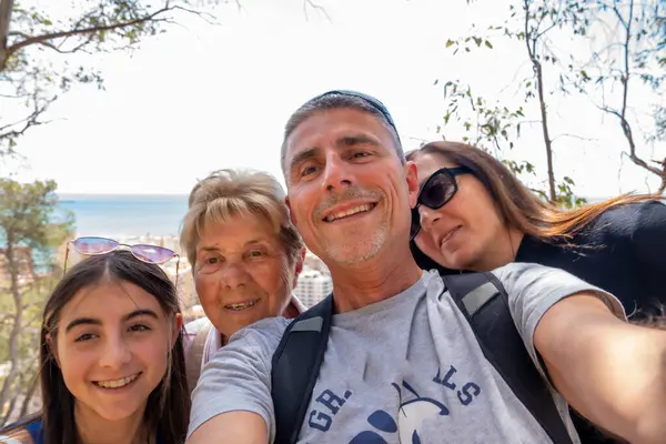 A happy family of four people enjoy outdoor time taking selfies.