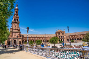 Sevilla, İspanya - 10 Nisan 2023: Güneşli bir günde Plaza de Espana boyunca turistler.