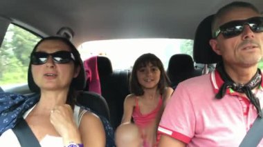 Neşeli, genç, geleneksel ailenin uzun bir araba yolculuğu var. Yaz Gezisi. Üç kişilik mutlu bir beyaz aile, araba sürüyor ve otomobille gezerken eğleniyorlar..