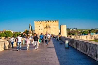 Cordoba, İspanya - 11 Nisan 2023: Turistler gün batımında Roma köprüsü boyunca yürürler.