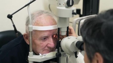 Kıdemli doktor, göz muayenesi ve doktor muayenesinde tıbbi gözleri olan bir optometrist. Görüş, sağlık hizmeti odağı ve lens ve gözlük kontrolü için danışmanlık uzmanına sahip yaşlı bir erkek hasta..