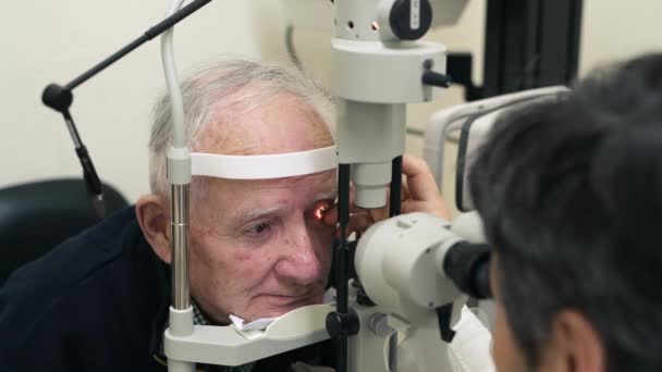 医師の診察で医師の診察を受けるシニアマン 眼科検査および眼科医 レンズや眼鏡検査のためのコンサルティングウェルネスエキスパートとのビジョン ヘルスケアの焦点 老人患者 — ストック動画