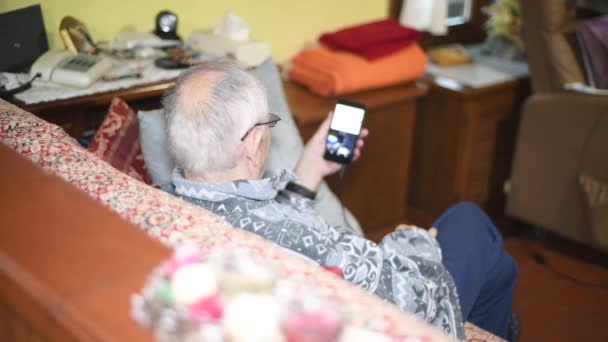 Oudere Man Zit Bank Met Zijn Smartphone Thuis — Stockvideo