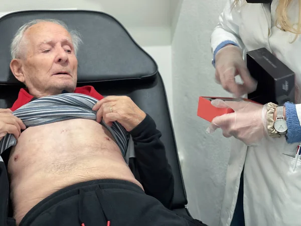 An elderly man in the hospital while having his Holter applied.