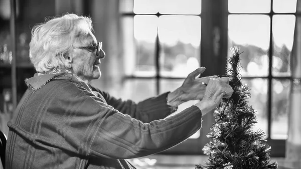 Starší Žena Zdobí Vánoční Stromek Doma — Stock fotografie