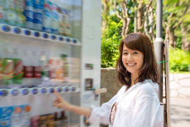 Kendine güvenen güzel Asyalı kız otomattan içecek seçiyor..