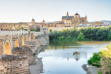 Cordoba, İspanya - 11 Nisan 2023: Turistler gün batımında Roma köprüsü boyunca yürürler.