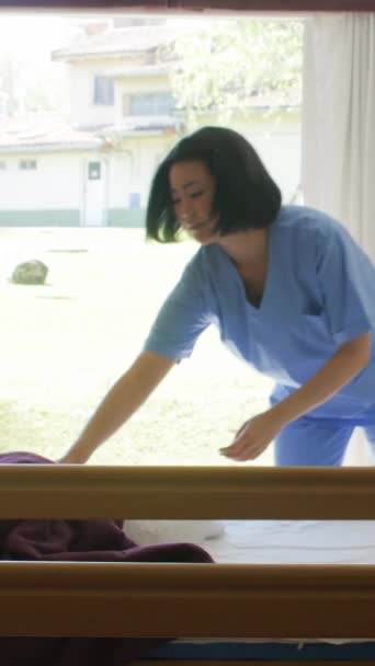 Aziatische Verpleegster Die Een Ziekenhuisbed Opmaakt Verticale Video Stockvideo's