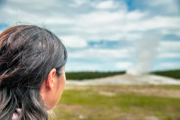 stock image Woman witnessing the eruption of Old Faithful Geyer, Yellowstone National Park.