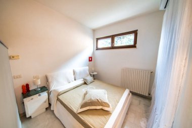 Beyaz duvarları ve komodinleri olan güzel, sıcak bir yatak odası..