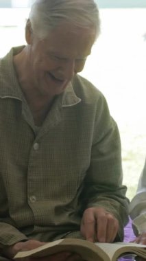 İki yaşlı insan yatakta birlikte vakit geçiriyorlar. Dikey Video.