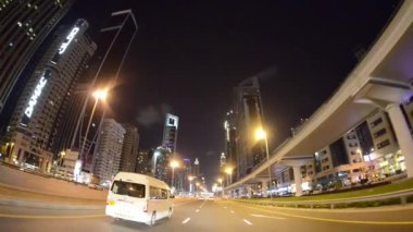 Gece Dubai şehir merkezindeki binalar ve gökdelenler Şeyh Zayed Yolu 'ndaki hareket halindeki bir arabadan..