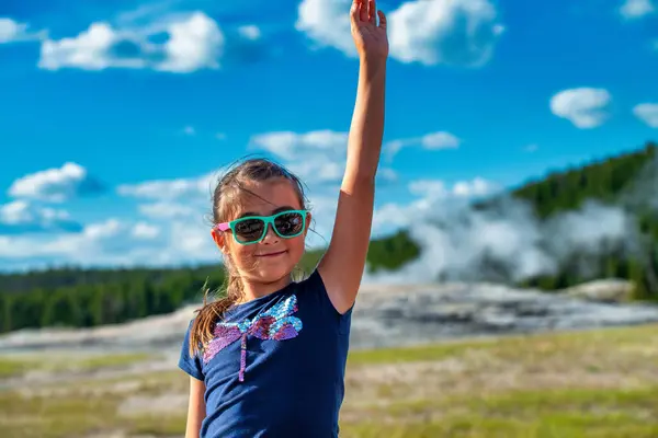 stock image Happy young girl in front of famous Old Faithful Geyser, Yellowstone National Park. 