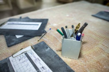 Kirli bir çalışma ortamında masa üzerindeki kalemler ve klasörler.