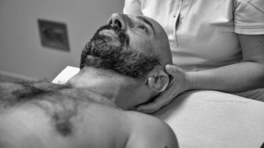 Osteopat, bir erkeğin omzuna kanepede fizyoterapi uyguluyor..