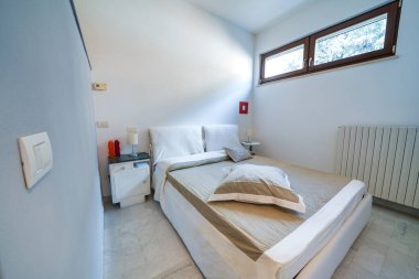 Yatak ve Kahvaltı tek odalı daire, beyaz iç tasarım, açık alan, komodinli yatak odası..