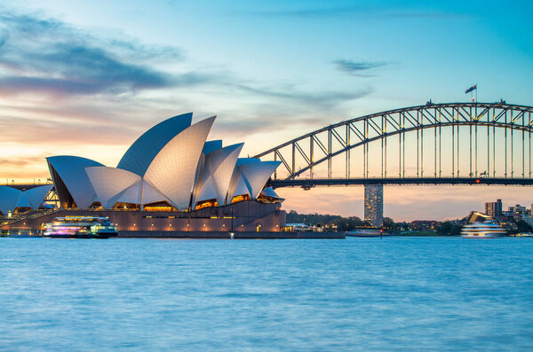 Sydney Harbour Bridge and Opera House Glowing in Evening Blue Hour.