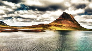 Arkasında göl ve okyanus olan ünlü İzlanda dağı Kirkjufell. Kirkjufell Dağı, yaz mevsiminde Snaefellsnes Yarımadası 'nda İHA bakış açısıyla.