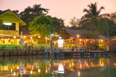 Amphawa Yüzen Pazarı 'nın gece görüşü. Nehir boyunca. Sudaki ışıkların yansımaları..