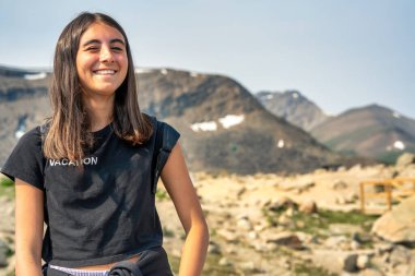 Genç kız, doğa güzelliği ve sükunetle çevrili bir dağ yolunda huzur içinde dinleniyor.. 