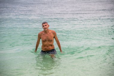 Berrak mavi su ve altın güneş ışığıyla tropik bir cennette yüzen bir gezgin..