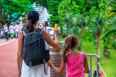 Sırt çantalı annenin ve sokakta yürüyen kızının arka görüntüsü.