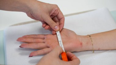 Tıp terapisti rehabilitasyon kliniğindeki bir kız için el bandı ayarlıyor..