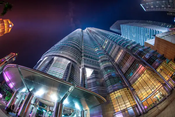 Kuala Lumpur, Malezya - 27 Aralık 2019: Iconic Petronas Kuleleri gece parlıyor, aşağıdaki hareketli sokaklardan yakalandılar.