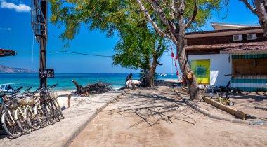Gili Trawangan, Endonezya - 26 Ağustos 2023: Güneşli bir günde Gili Trawangan 'ın güzel yollarında bisiklet sürmek.