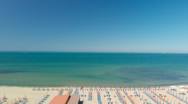 Renkli şemsiyeli ve yaz tatili atmosferli sahil beldesinin insansız hava aracı görüntüsü..