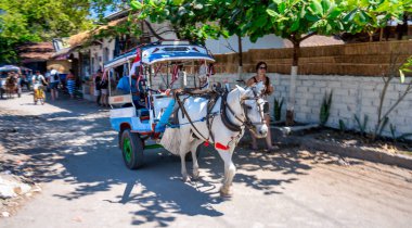 Gili Trawangan, Endonezya - 26 Ağustos 2023: Gili Trawangan 'ın güzel sokaklarında güneşli bir at arabası gezisi.