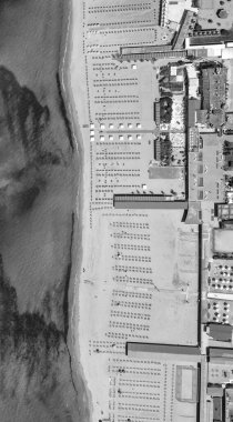 Kumlu sahil şeridindeki dinlenme yerleri ve şemsiyeler de dahil olmak üzere sahil yapılarının hava perspektifi.