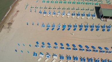 Renkli şemsiyeli ve yaz tatili atmosferli sahil beldesinin insansız hava aracı görüntüsü..