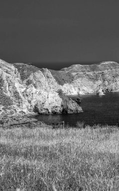 Engebeli dağları ve derin mavi Ege Denizi ile Santorini 'nin çarpıcı kıyı manzarası.