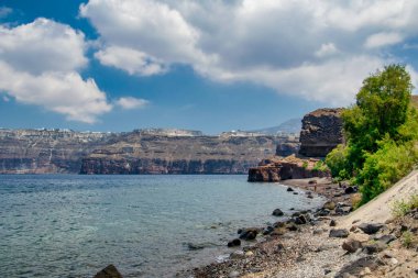 Engebeli dağları ve derin mavi Ege Denizi ile Santorini 'nin çarpıcı kıyı manzarası.