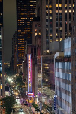 New York City, New York - 14 Haziran 2025: Manhattan gece caddeleri arasında parlayan Radio City Music Hall tabelasının yüksek açılı görüntüsü.