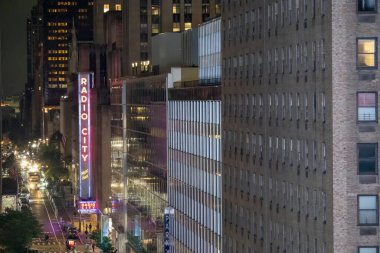 New York City, New York - 14 Haziran 2025: Manhattan gece caddeleri arasında parlayan Radio City Music Hall tabelasının yüksek açılı görüntüsü.