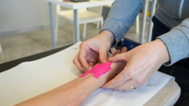 Fizyoterapist rehabilitasyon sırasında genç bir kadına el desteği hazırlar..