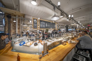 New York City - 14 Haziran 2025: New York 'taki Chelsea Market' in mağazaları, ışıkları ve endüstriyel tasarımı ile geniş bir iç görünümü.