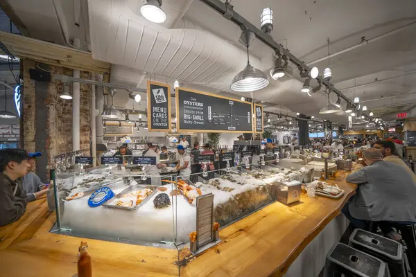 New York City - 14 Haziran 2025: New York 'taki Chelsea Market' in mağazaları, ışıkları ve endüstriyel tasarımı ile geniş bir iç görünümü.