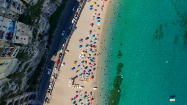 Tropea plajı güneşlenenlerle, şemsiyelerle ve sıcak bir günde dalgalarla görüldü..