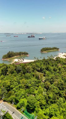Sentosa Adası 'nın panoramik insansız hava aracı perspektifi kıyı şeridi, çekim gücü ve açık mavi okyanusu gösteriyor..