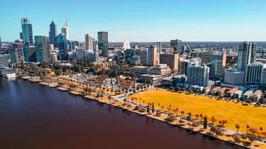 Kuğu Nehri 'nden Perth şehri berrak mavi gökyüzü ve güneşli gün yansımalarıyla.