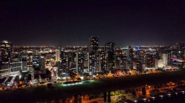 Perth merkez iş bölgesinin yüksek gökdelenleri ve parlayan ışıklarıyla insansız hava aracı görüntüsü..